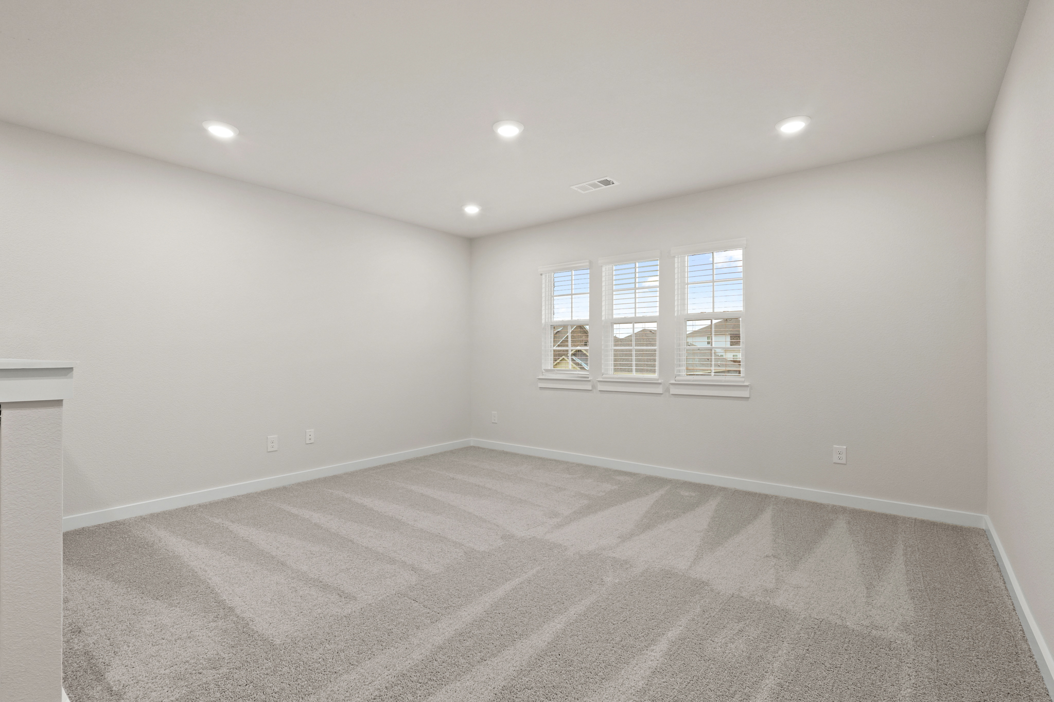A room with a white carpet and windows.