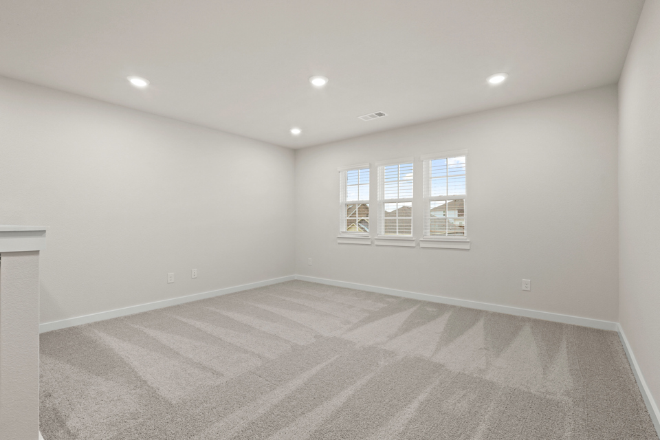 A room with a white carpet and windows.