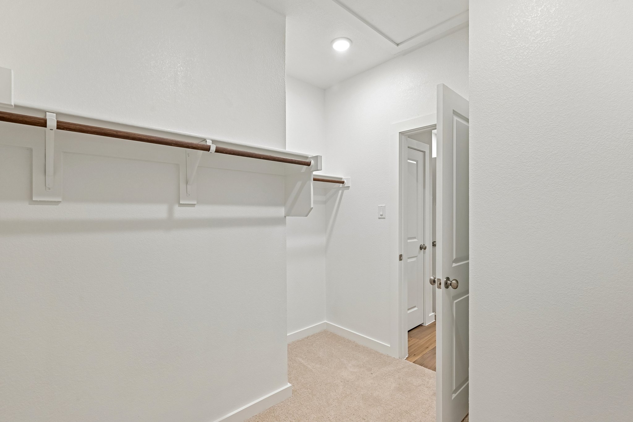 A white hallway with a white door.
