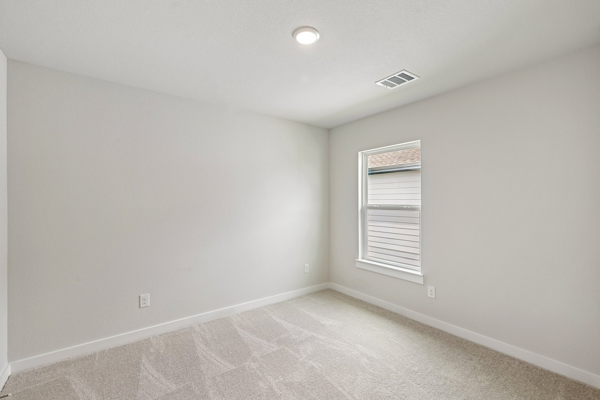 A room with a carpet and a light on the ceiling.
