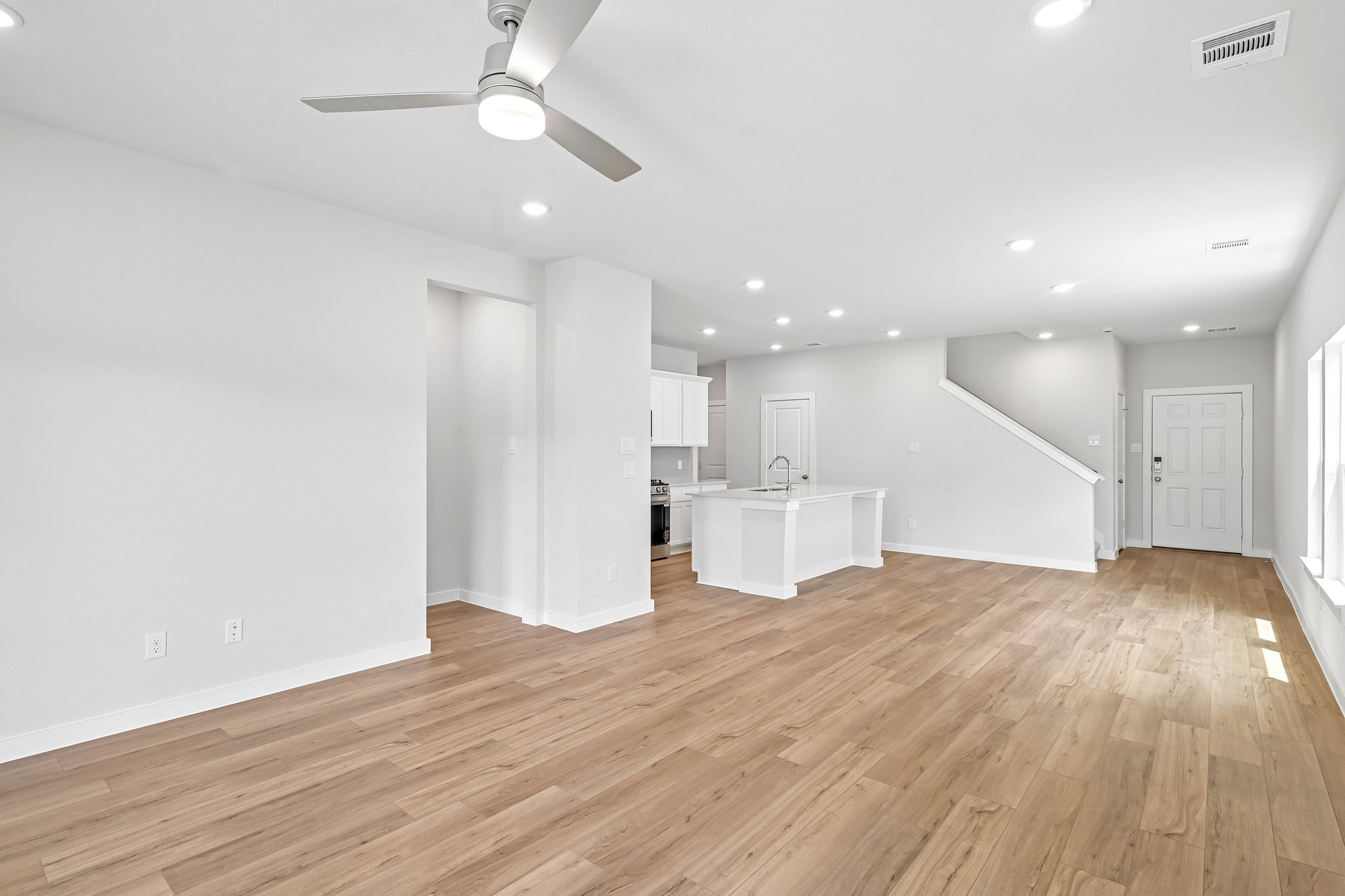 A large empty room with a wood floor and a white ceiling.