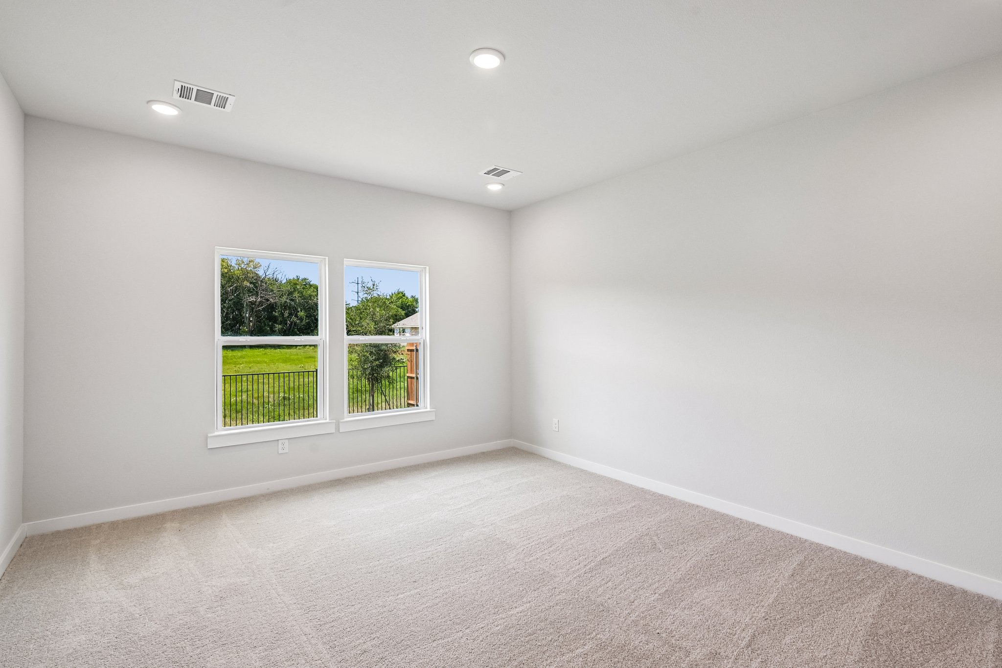 A room with a window and a white wall with a tree outside.