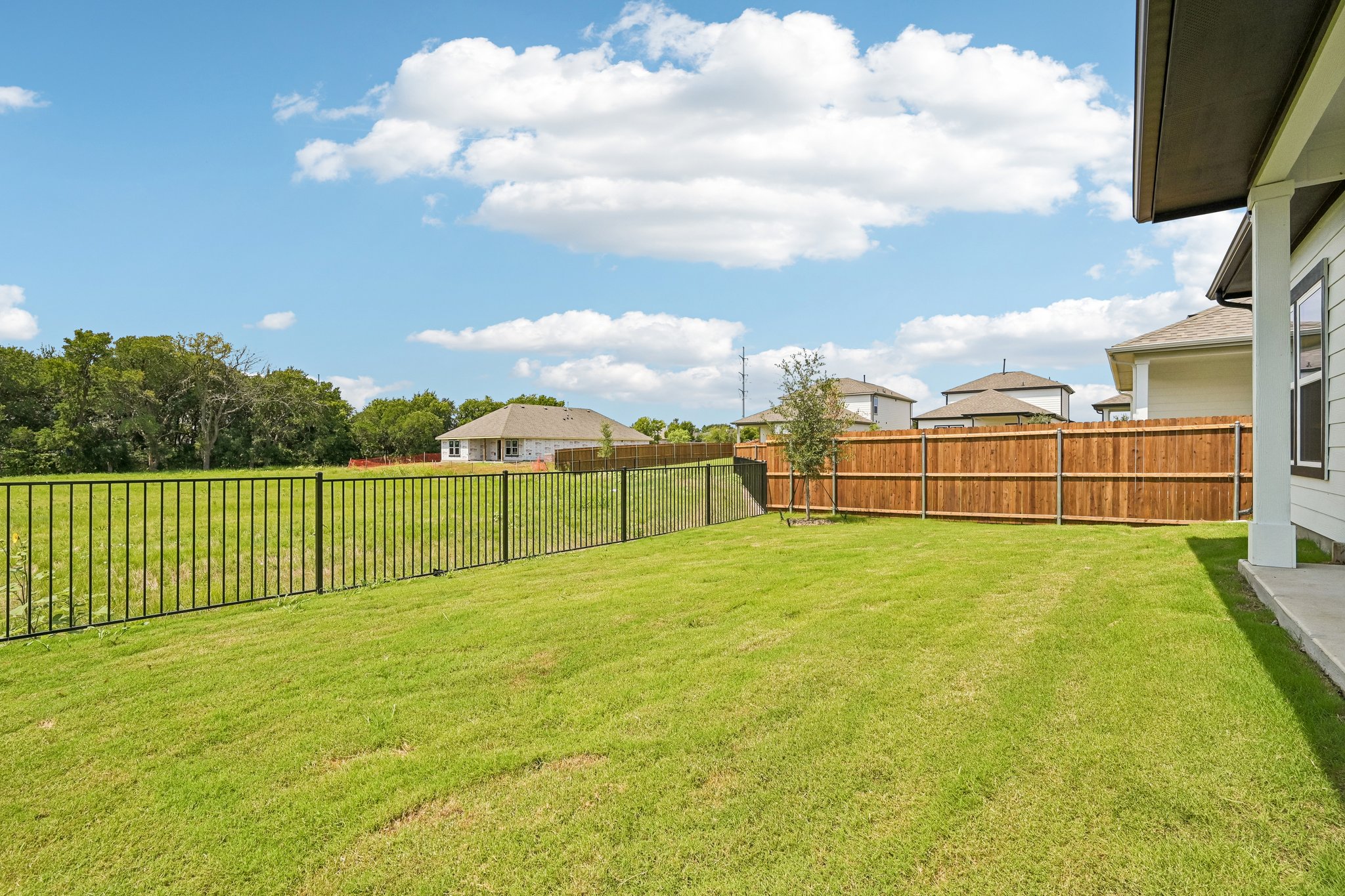 A fenced in yard with a house and trees in the background.