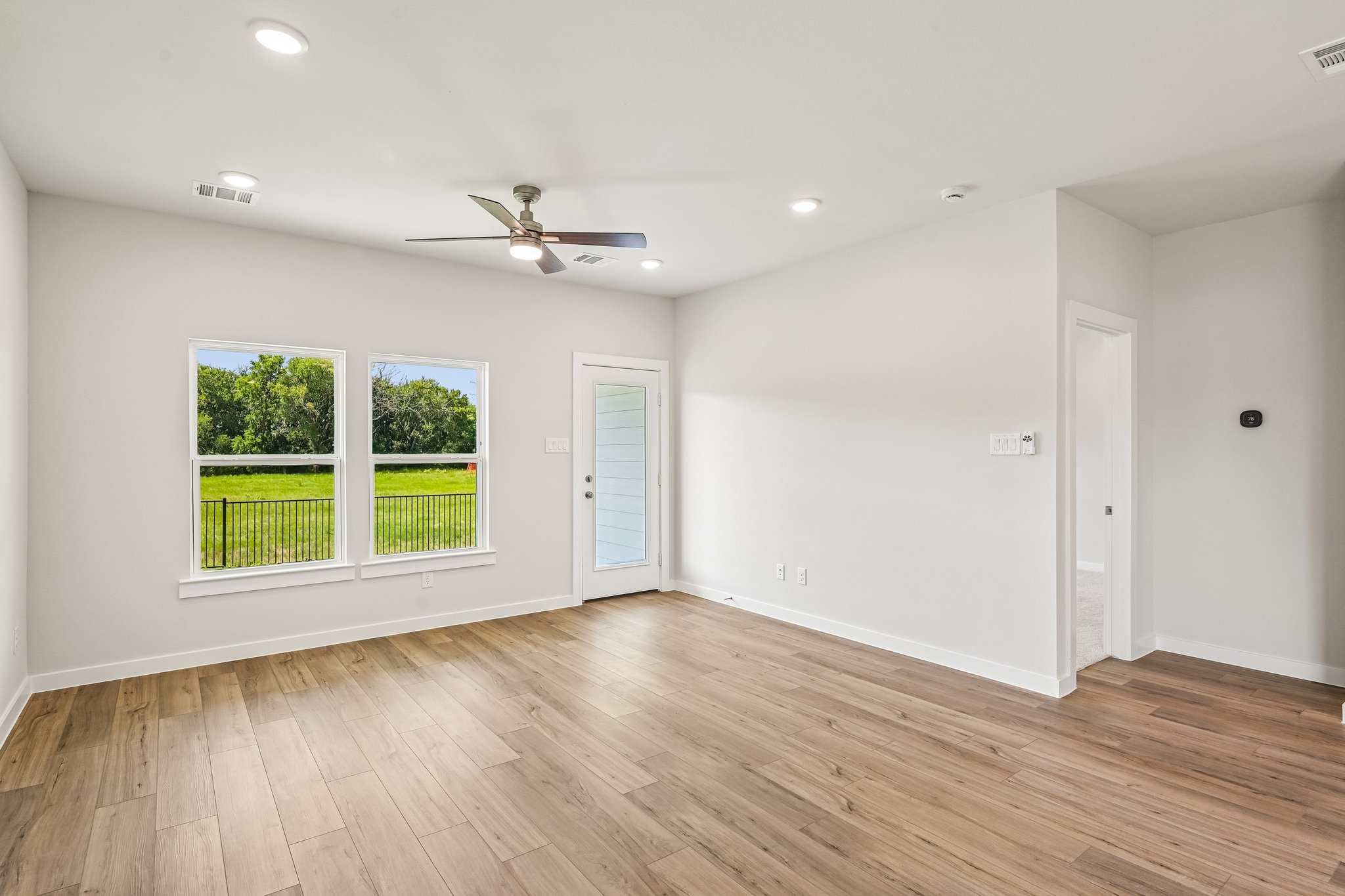 A room with a wood floor and a ceiling fan and a wood floor.