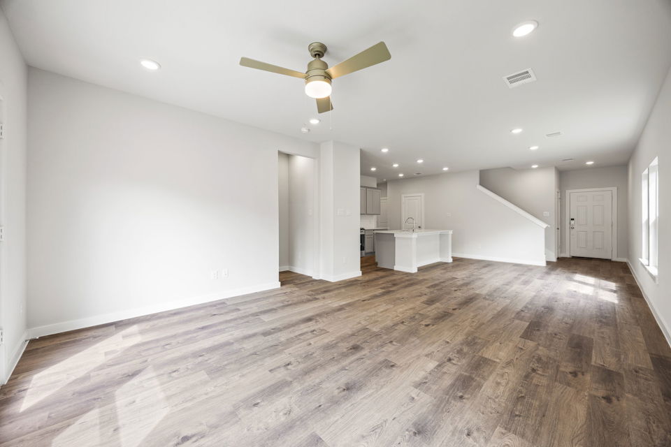 A large empty room with a wood floor and a ceiling fan.