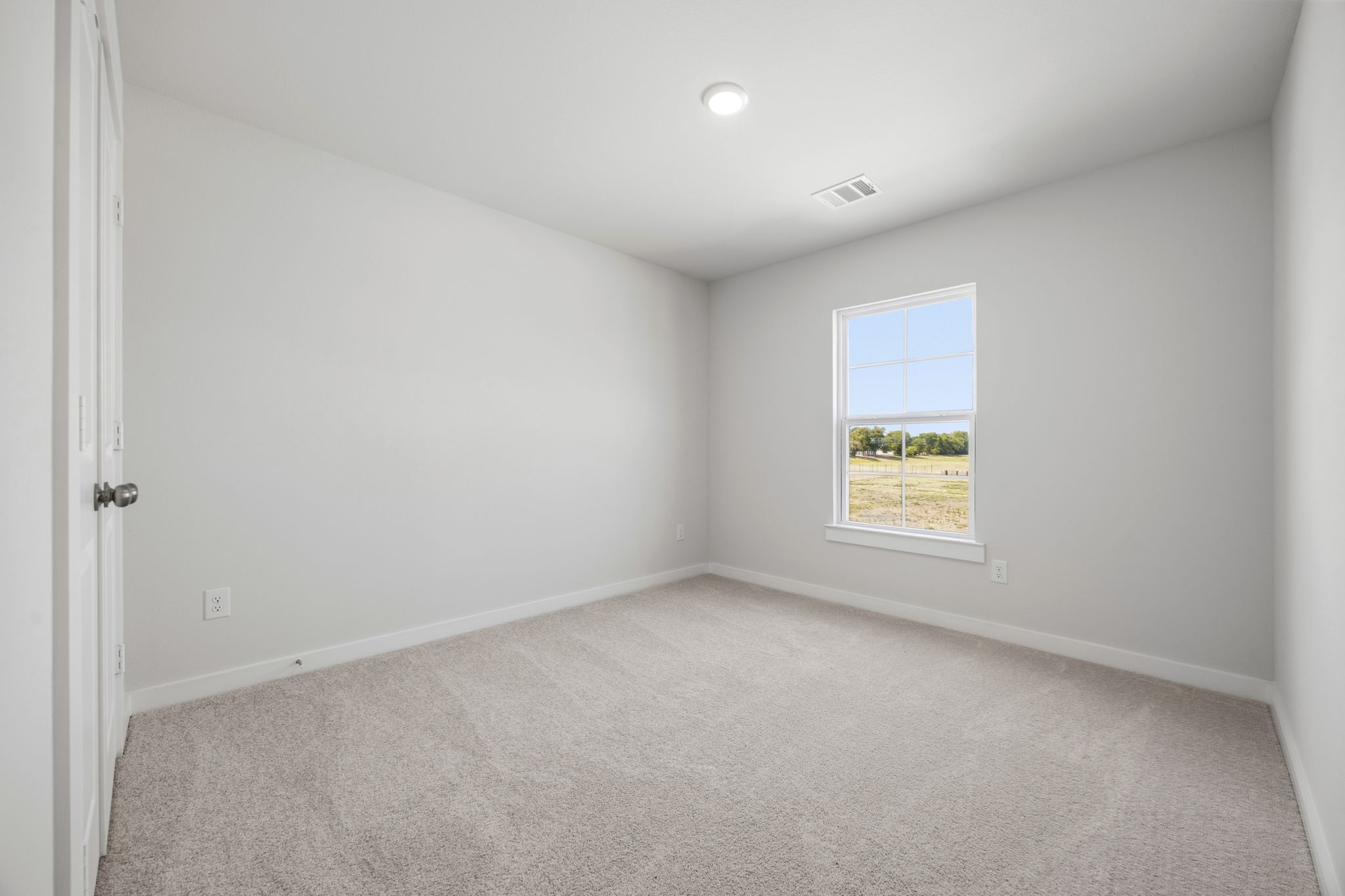 A room with a carpet and a window.