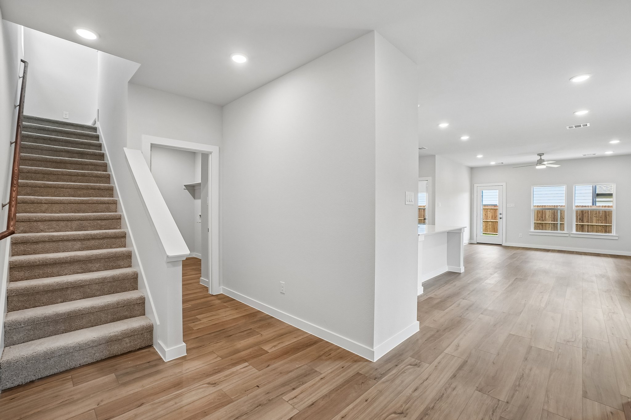 A large white room with a wood floor and a staircase.
