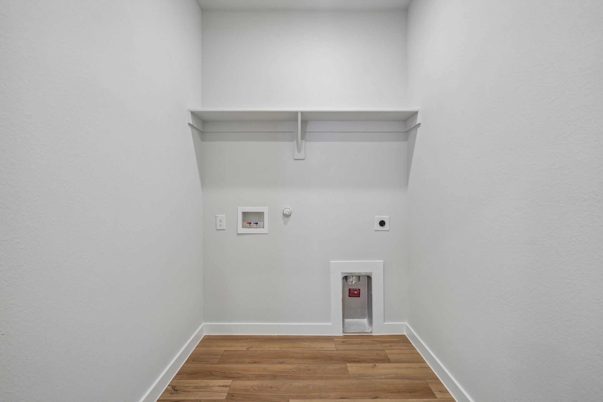 A white room with a wood floor and a white wall with a white door and a wood floor.