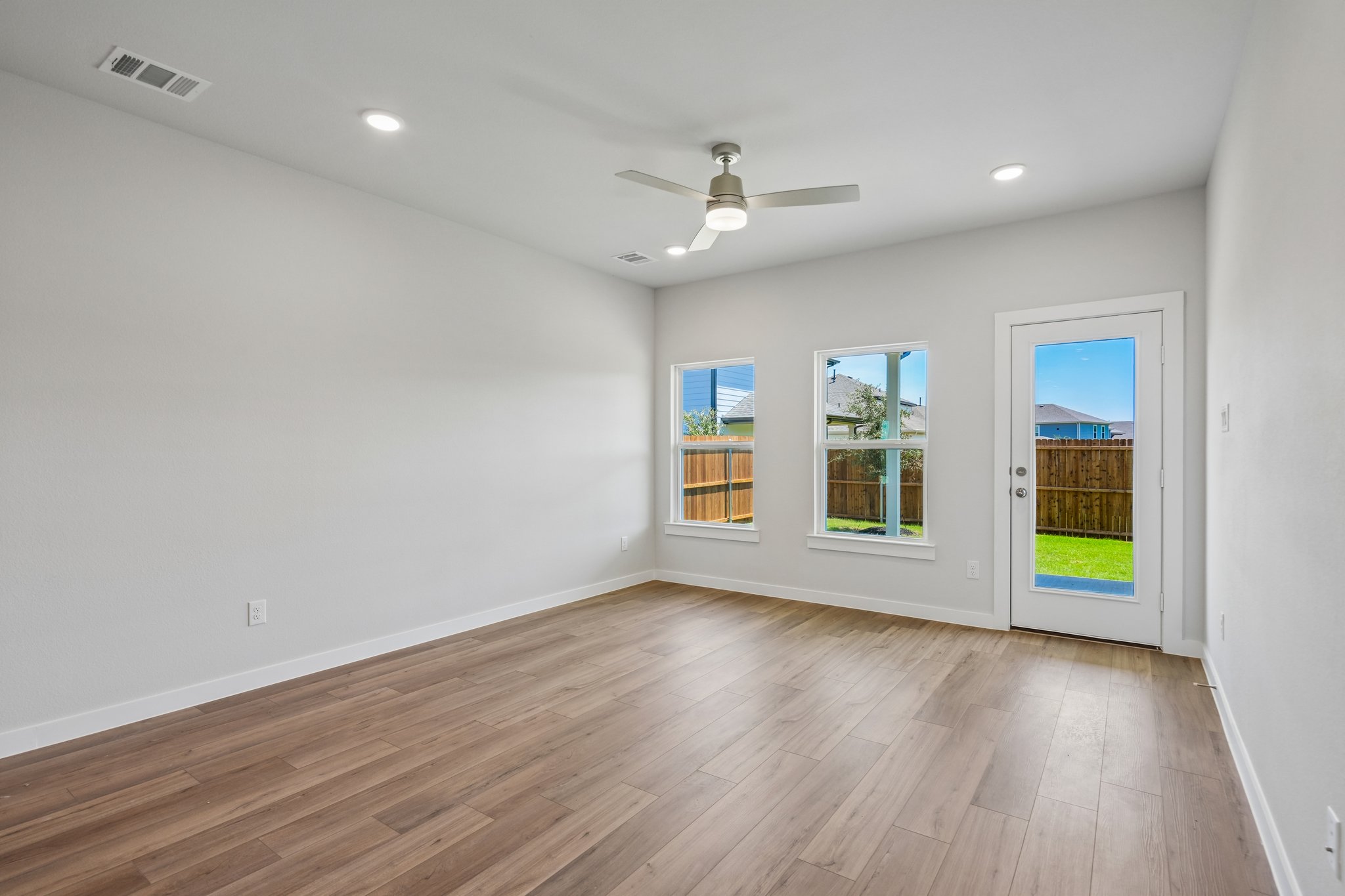 A room with a wood floor and a ceiling fan and a wood floor.
