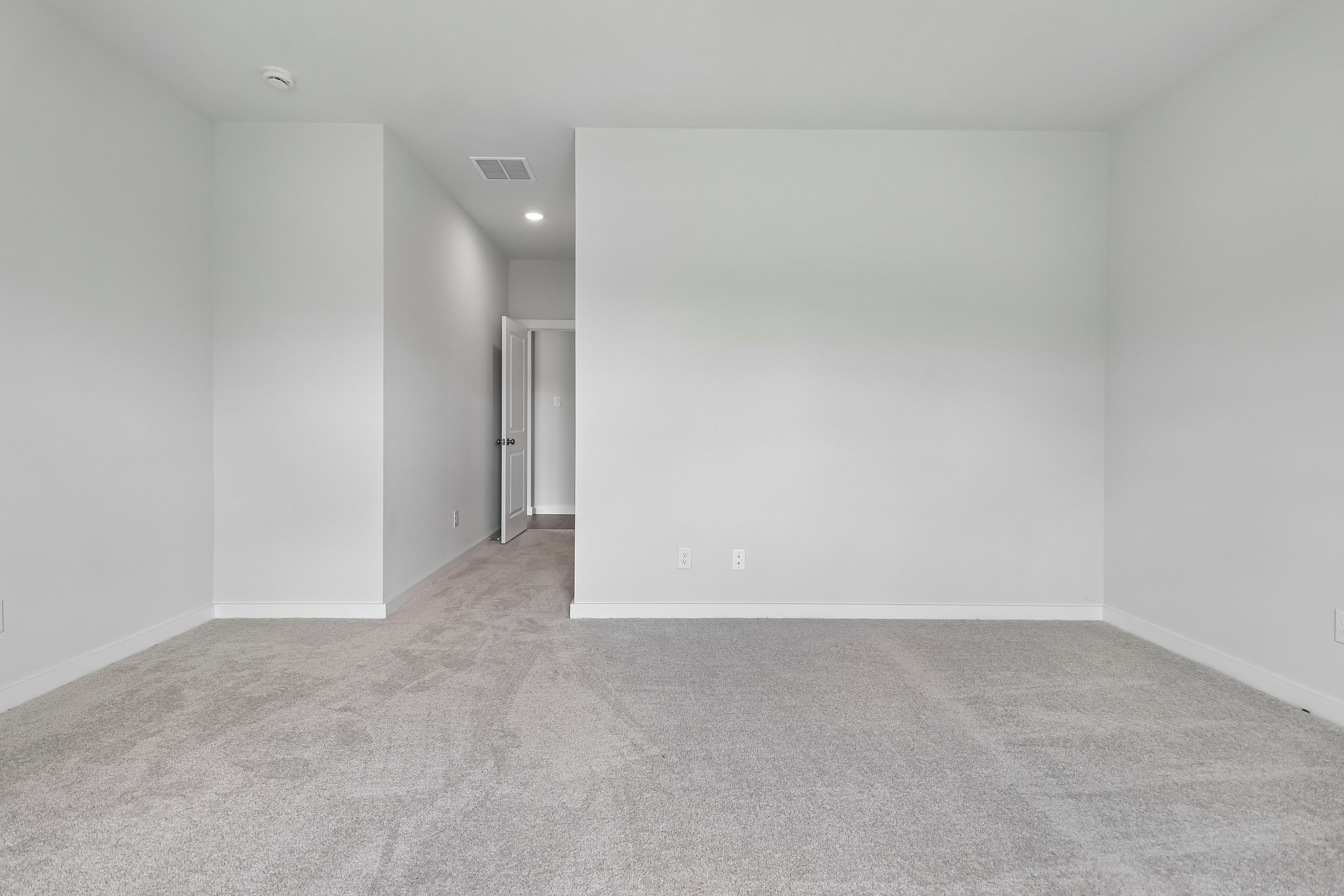 A room with a white wall and a carpet.