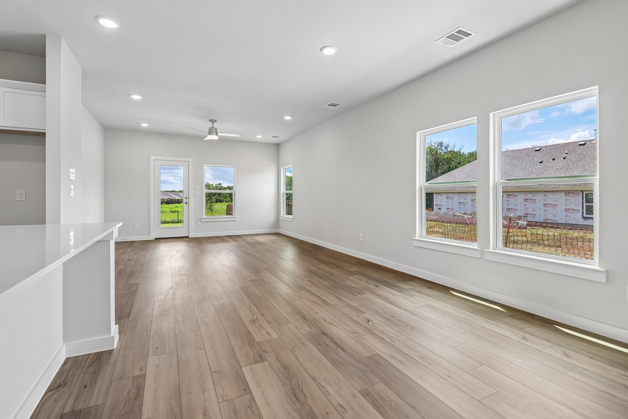 A room with a wood floor and a large window with a view of a city.