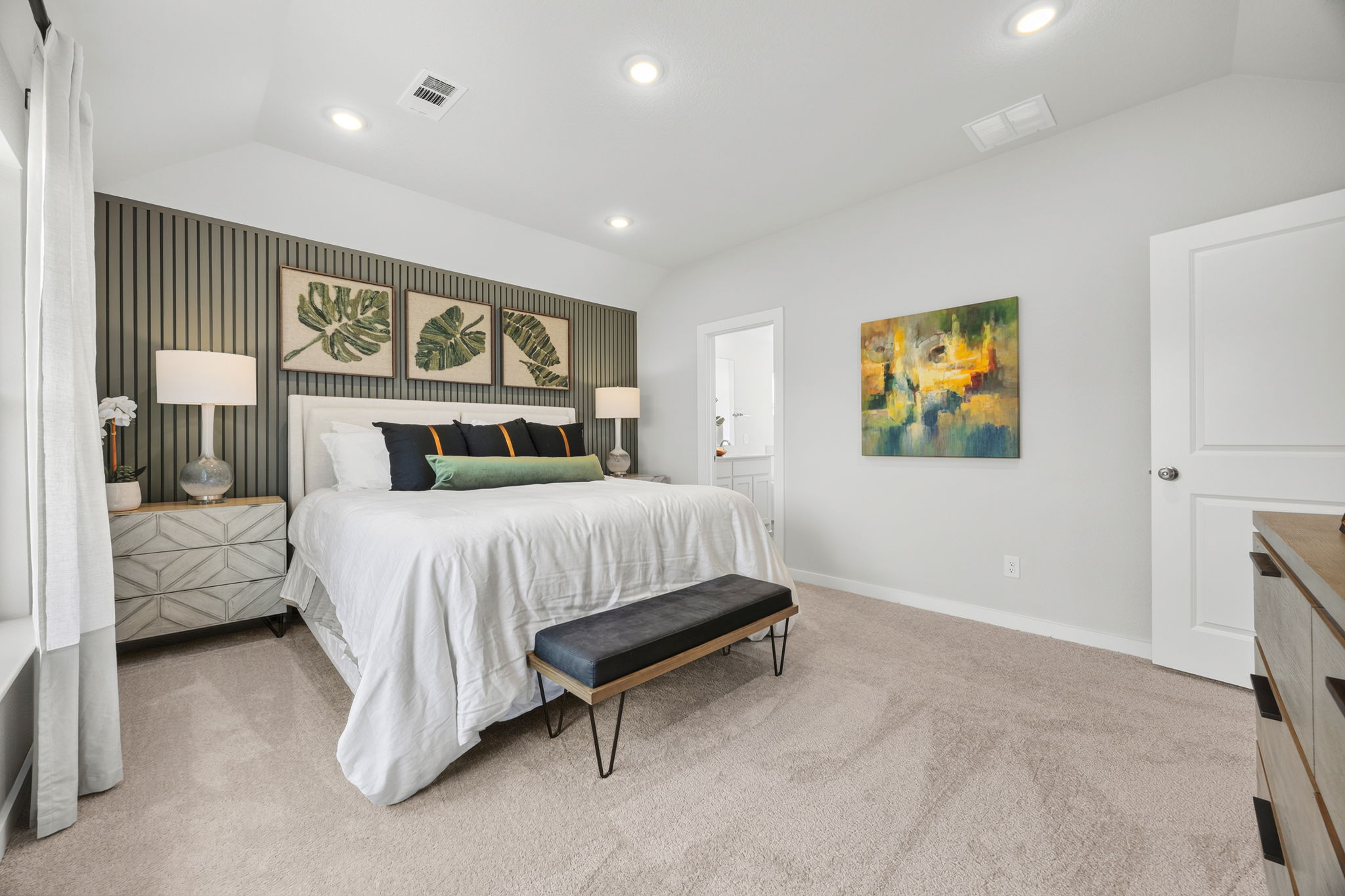 A bedroom with a bed and a bench.