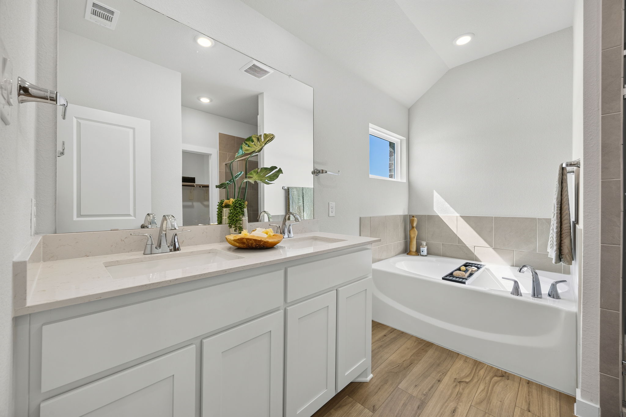 A bathroom with a tub sink and mirror.