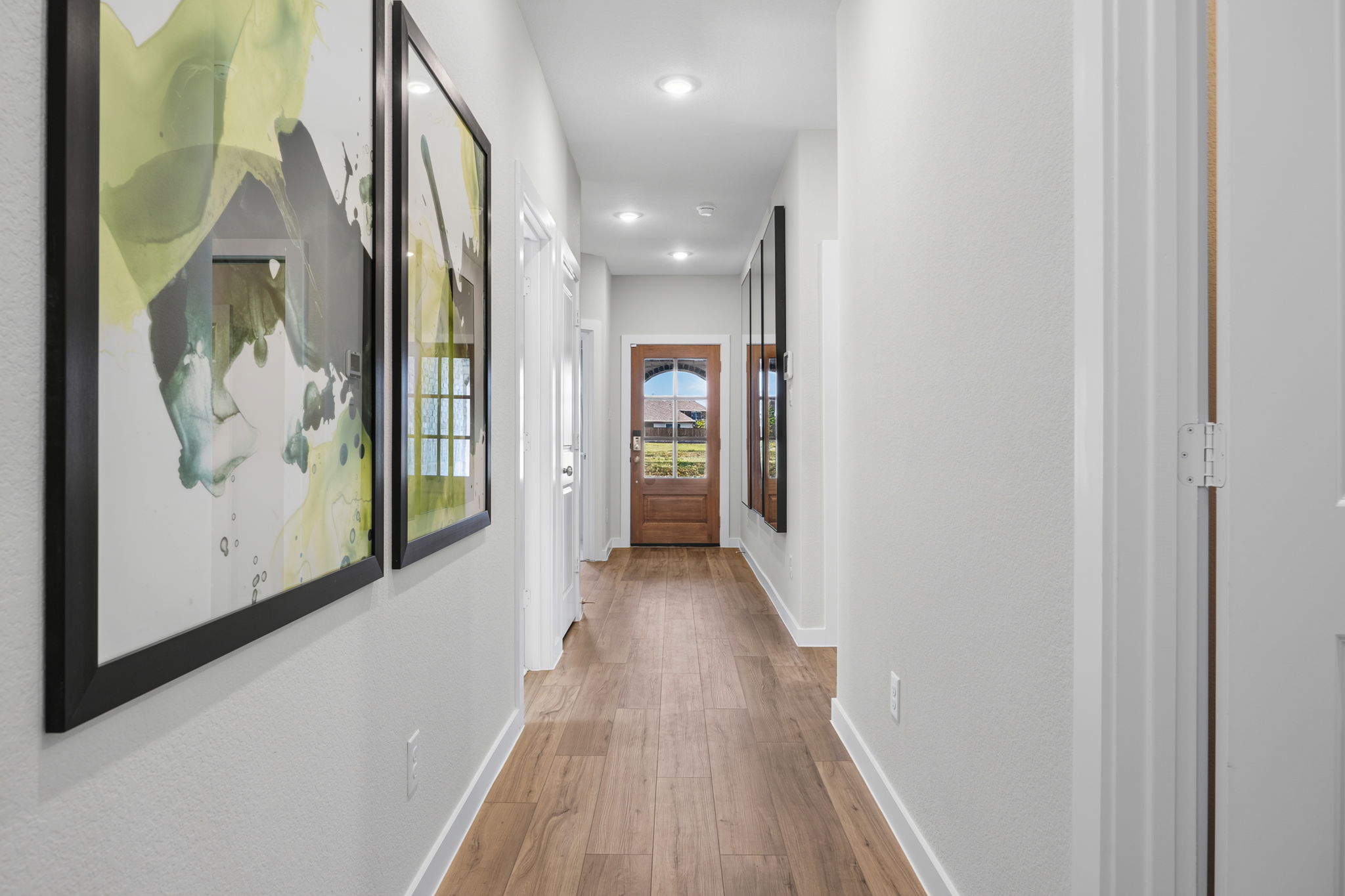 A hallway with a wood floor and white walls.