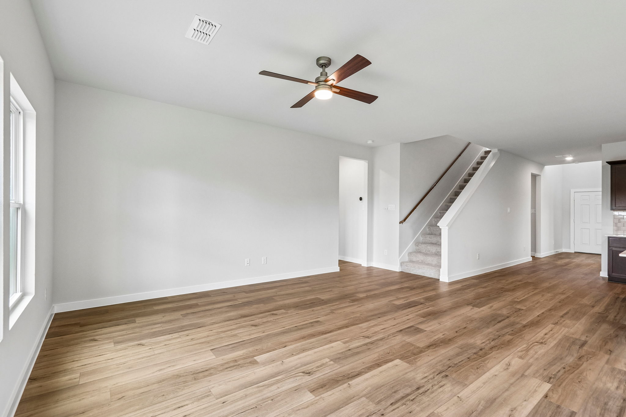 A room with a wood floor and a wood floor with a ceiling fan.