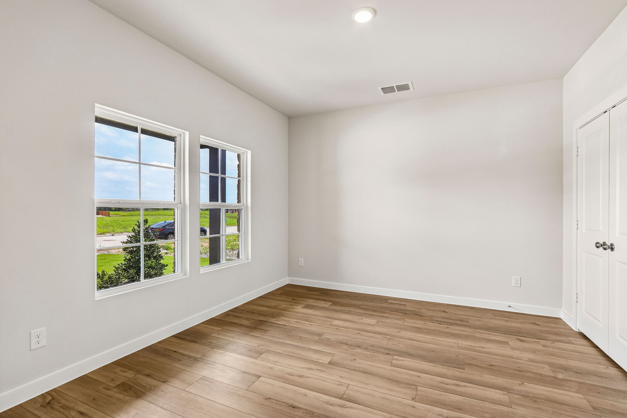 A room with a wood floor and windows.