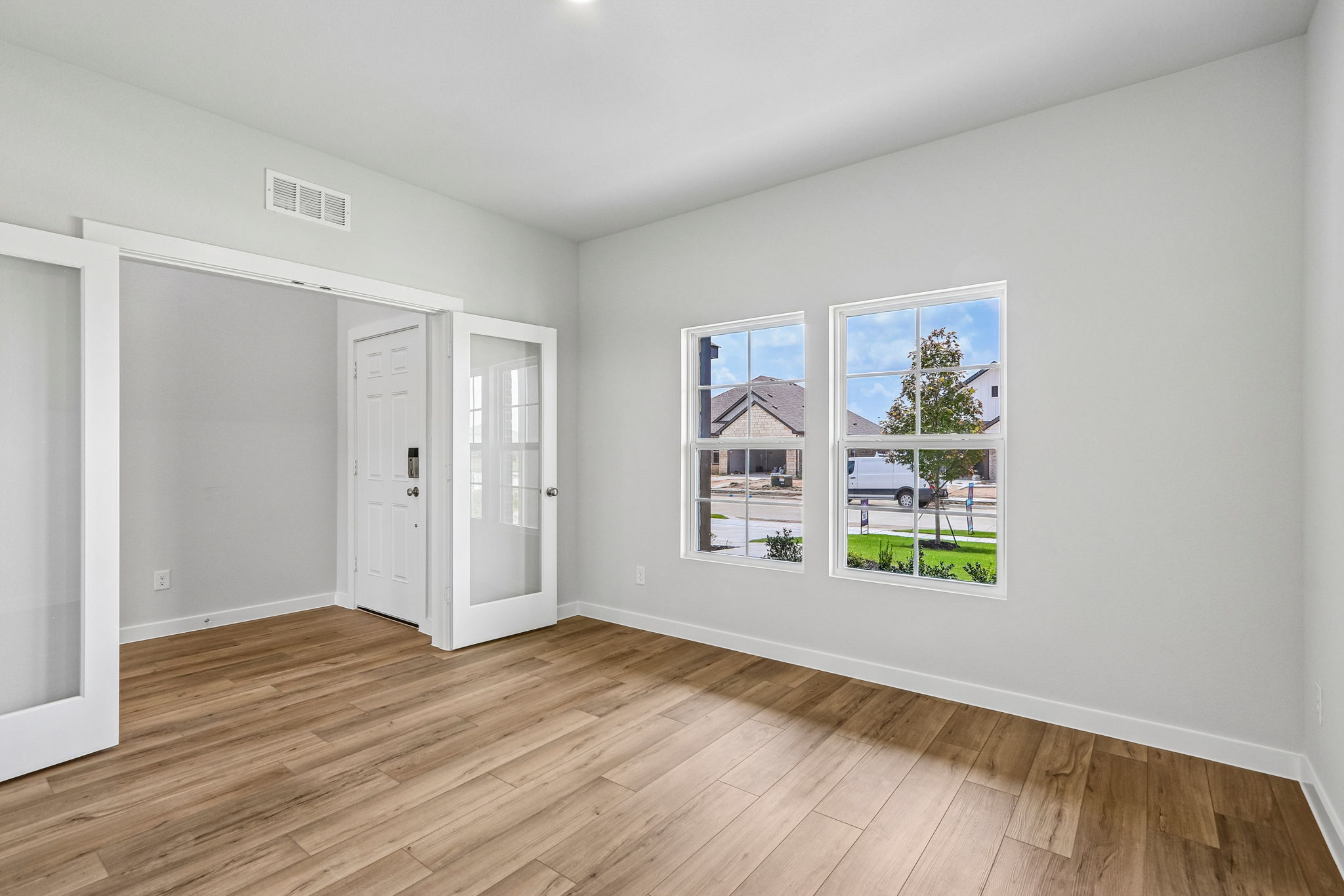 A room with a wood floor and a wood floor with a window.