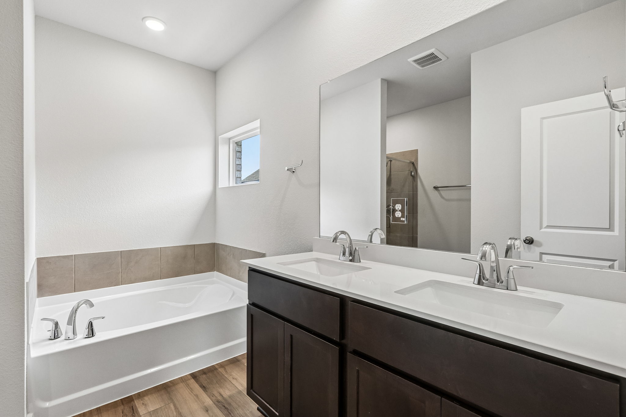 A bathroom with a tub sink and mirror.