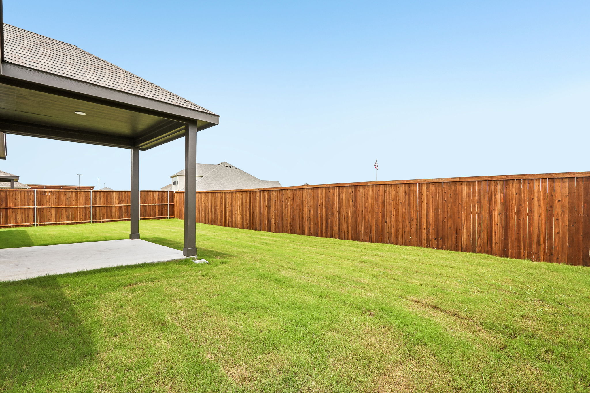 A fenced in yard with a wood fence and a building in the background.