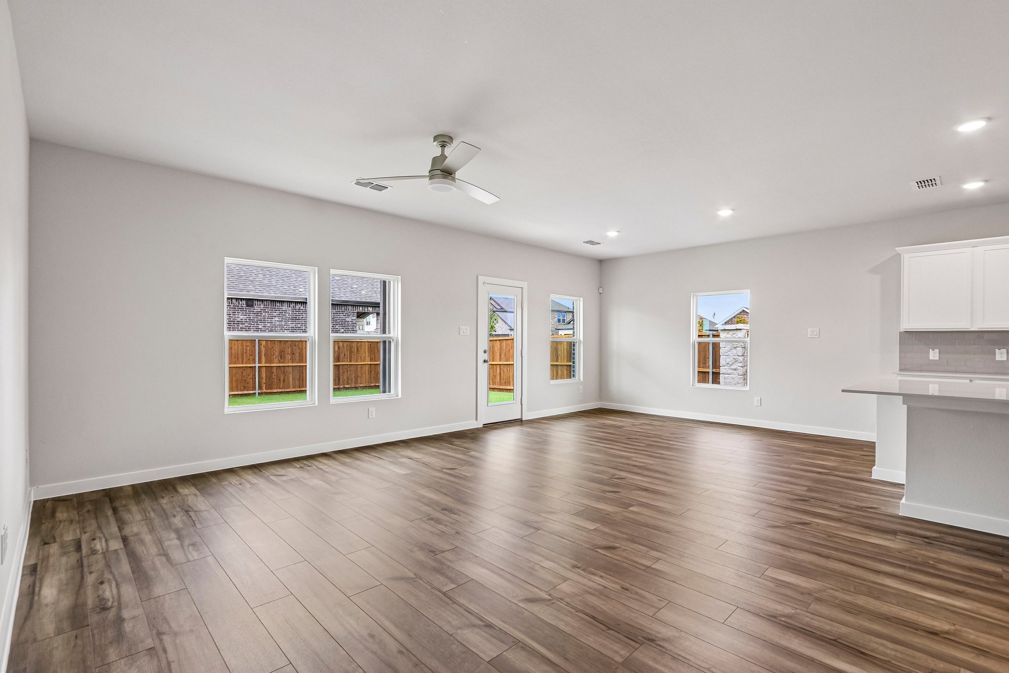A large empty room with a wood floor and a ceiling fan.