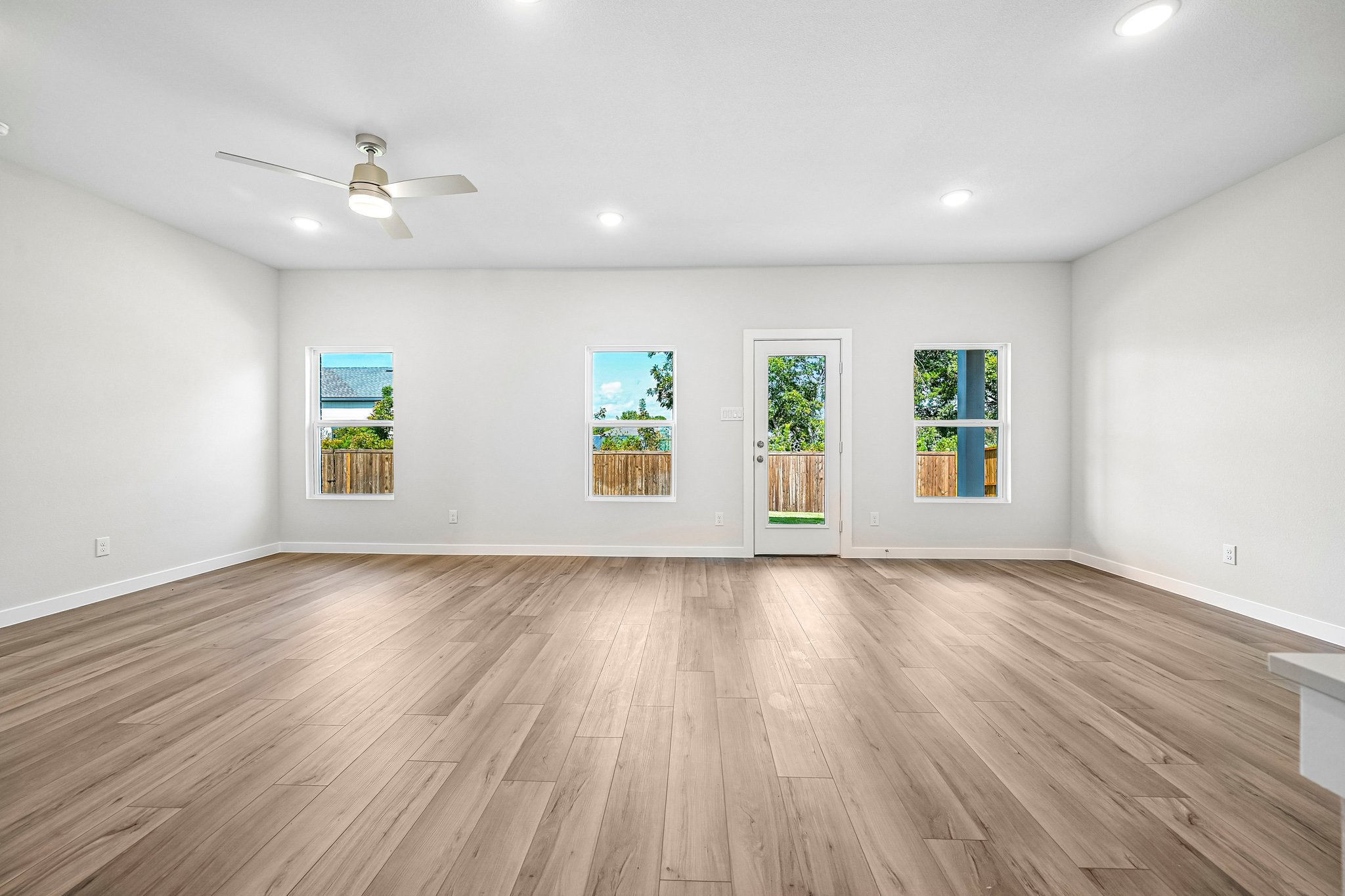 A room with a wood floor and a wood floor with a ceiling fan.