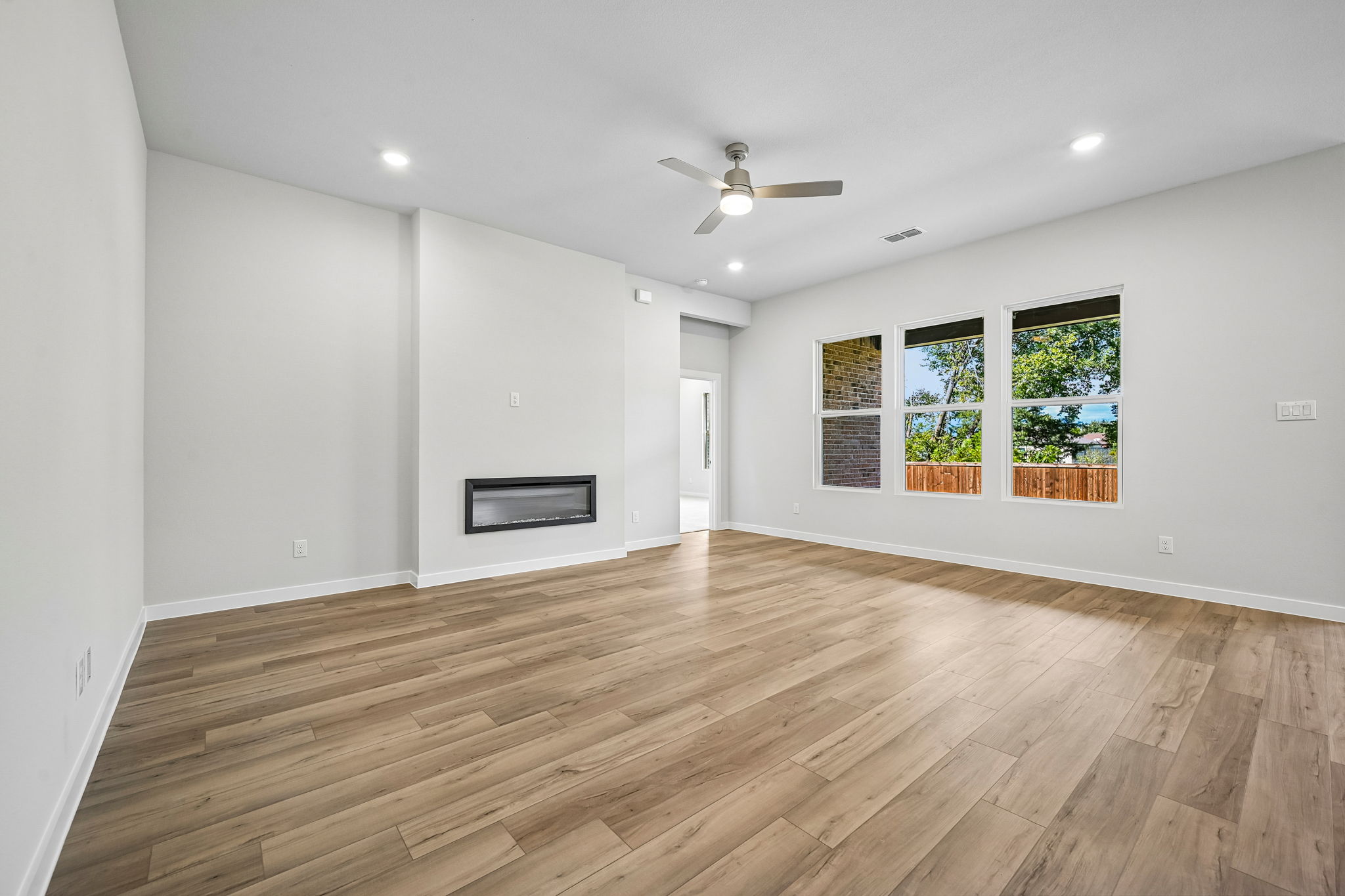 A room with a wood floor and a wood floor with a ceiling fan.