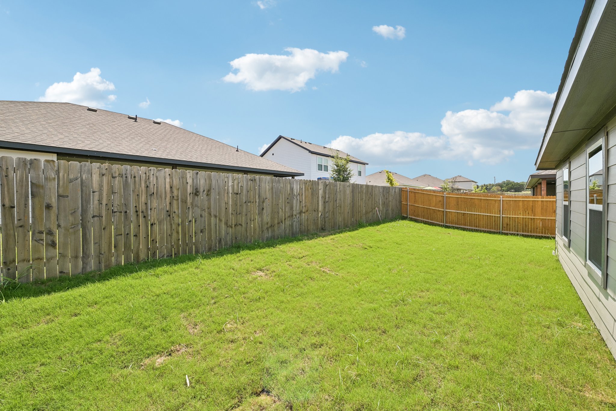 A fenced in yard with a house and a fence.