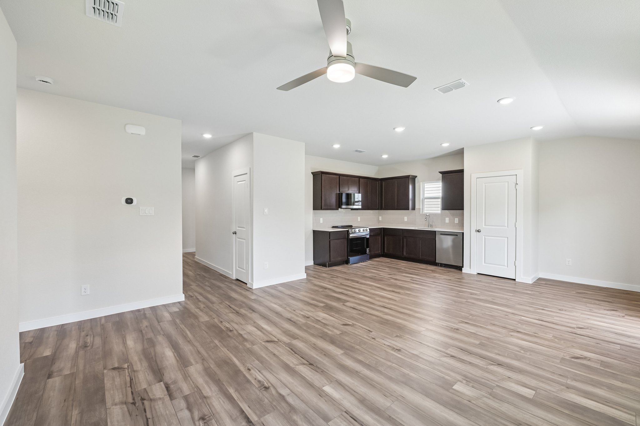 A large empty room with a wood floor and a ceiling fan.