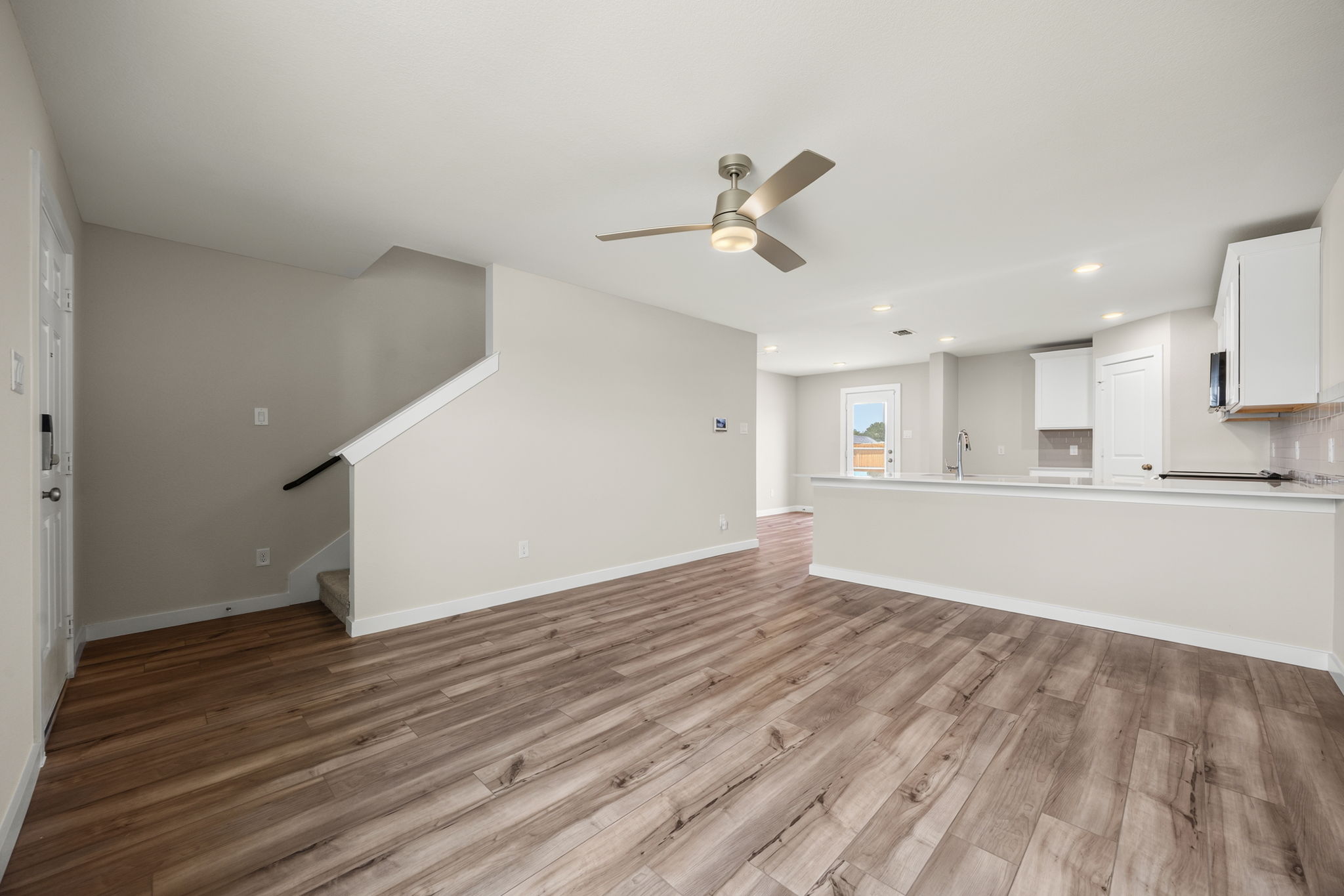 A large empty room with a wood floor and a ceiling fan.