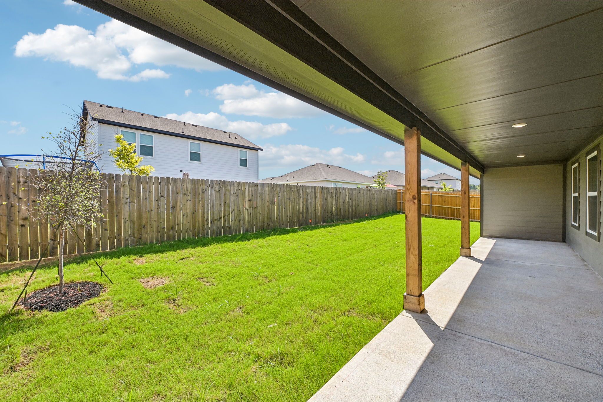 A fenced in yard with a tree and a house in the background.