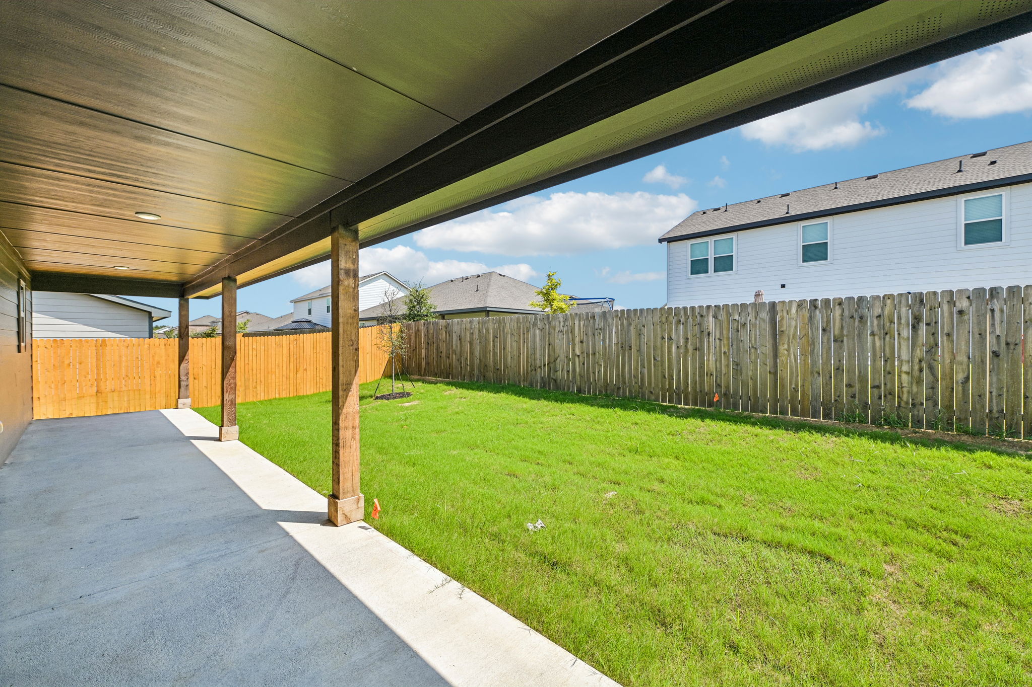 A fenced in yard with a walkway and grass and a building.