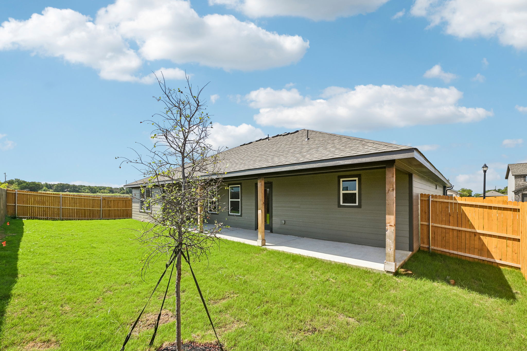 A house with a fence and a tree in the front.
