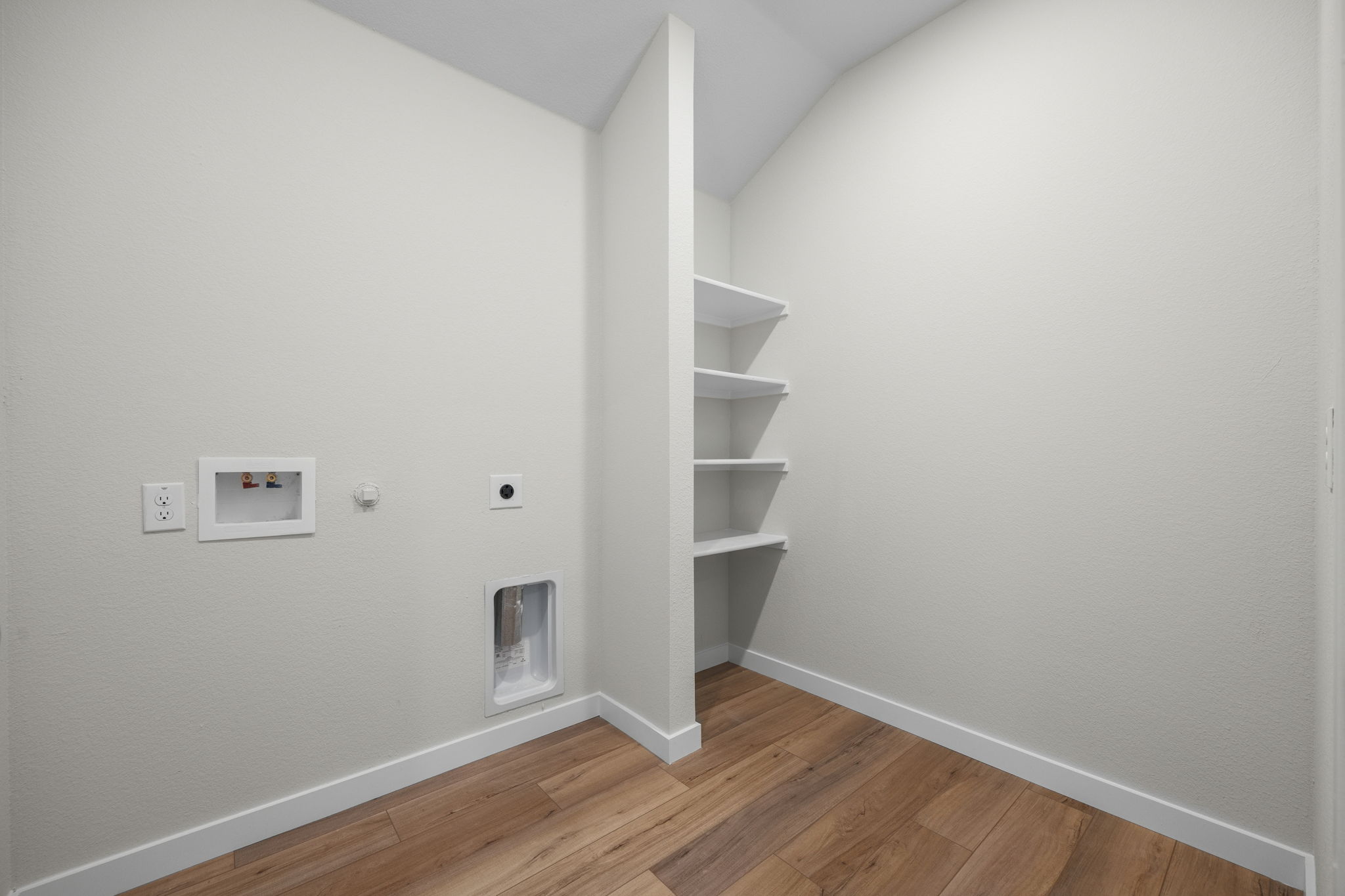 A white room with a wood floor and white walls.