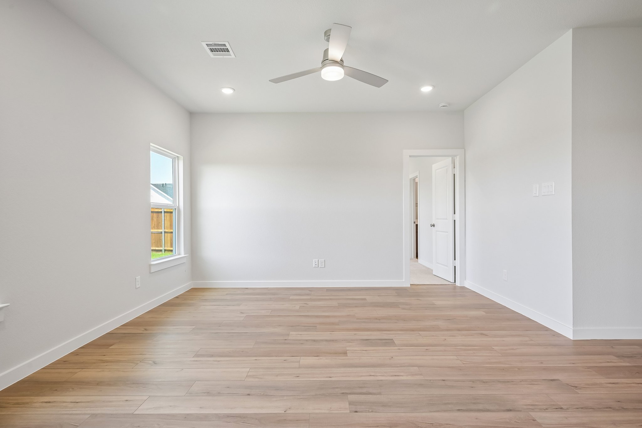 A room with a wood floor and a ceiling fan.