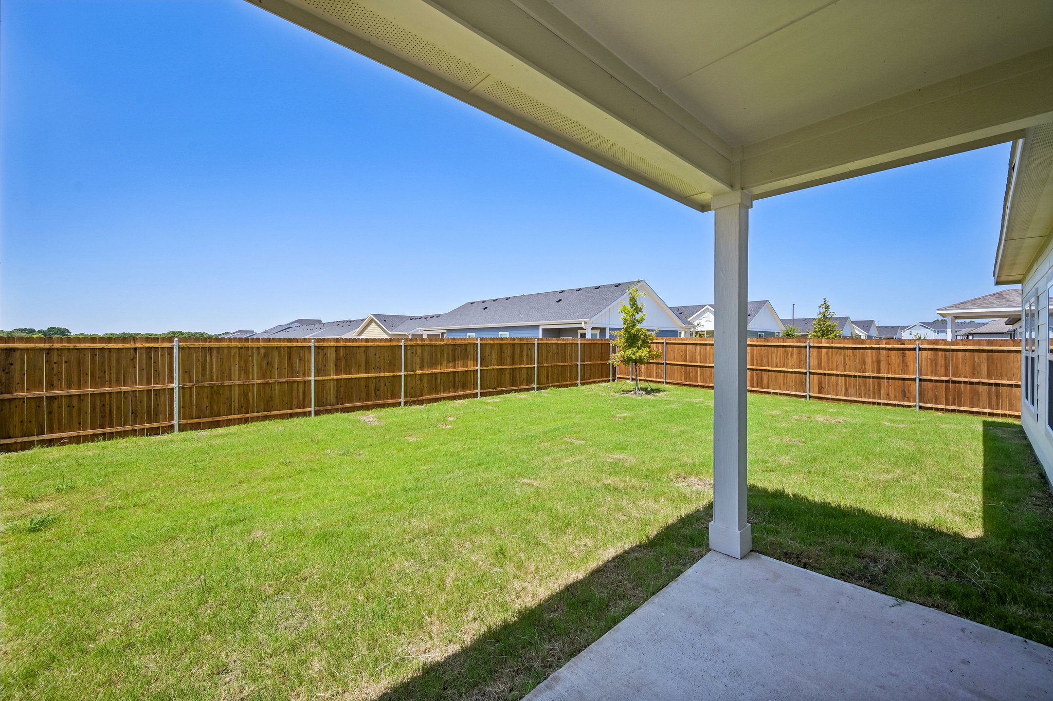 A fenced in yard with a wood fence and a tree.