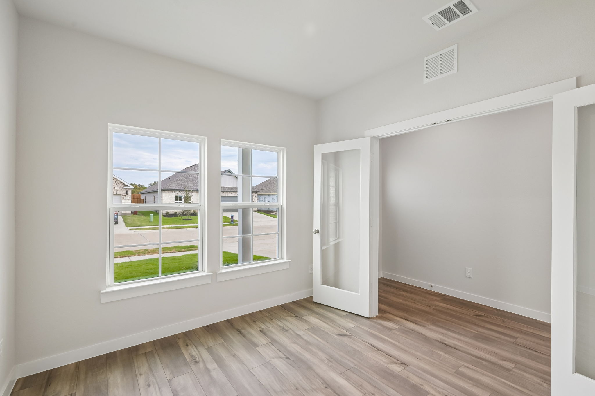 A room with a wood floor and a window with a view of the street.