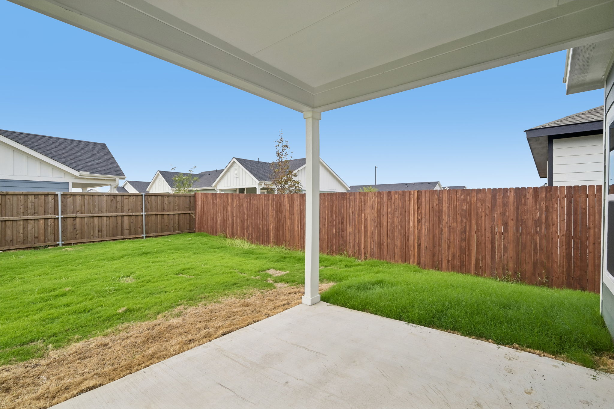 A fenced in yard with a wood fence and a house in the background.