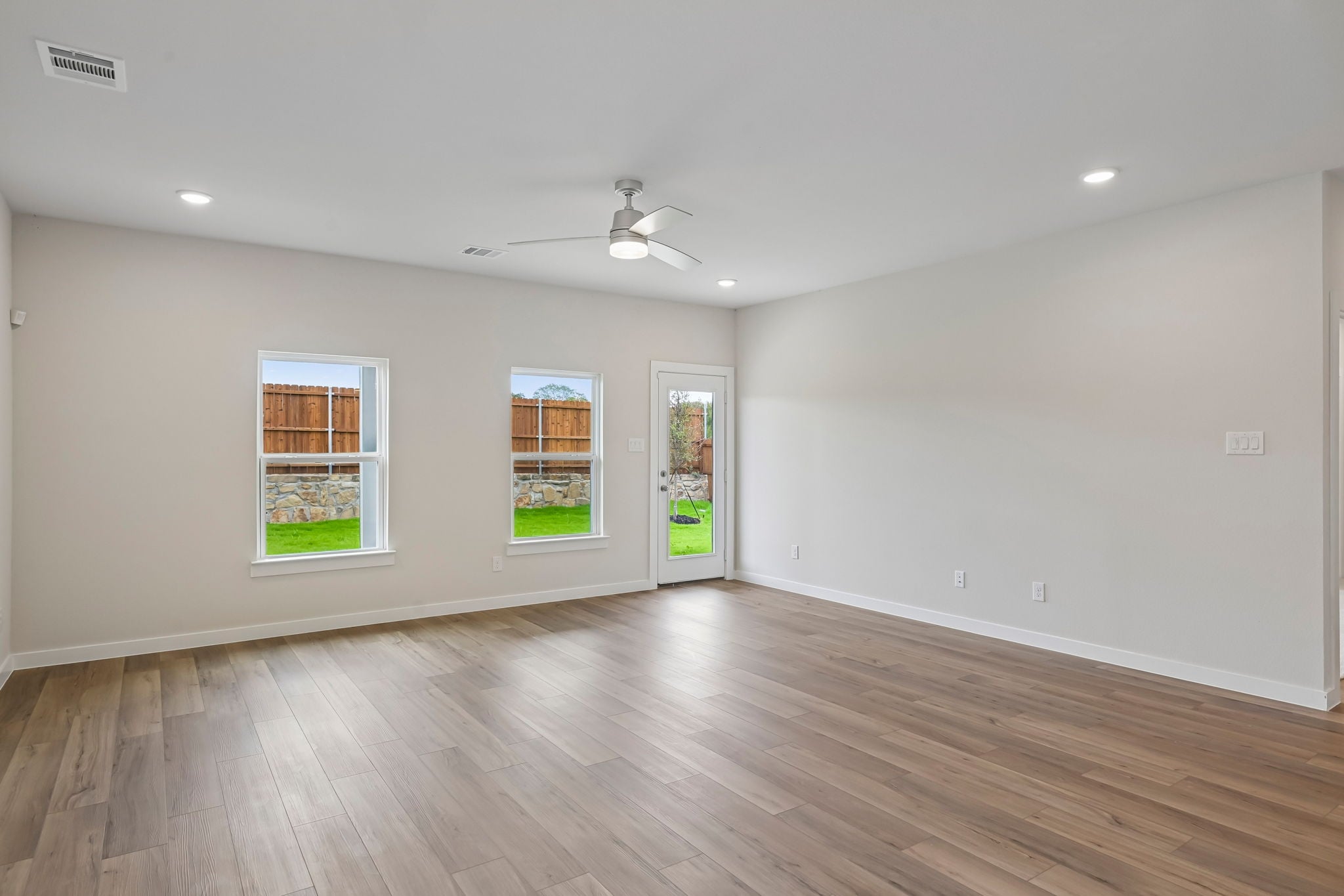 A room with a wood floor and a ceiling fan and a wood floor.