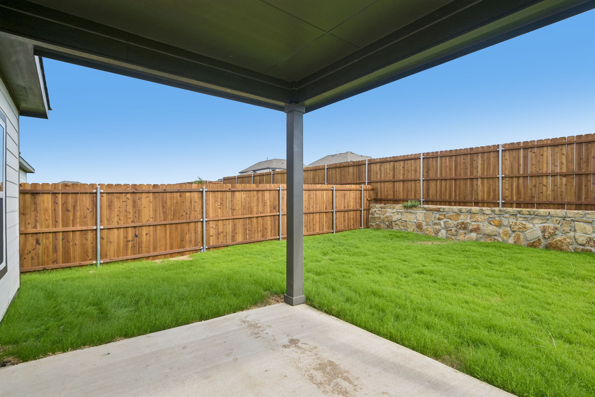 A fenced in yard with a stone wall and a wood fence.