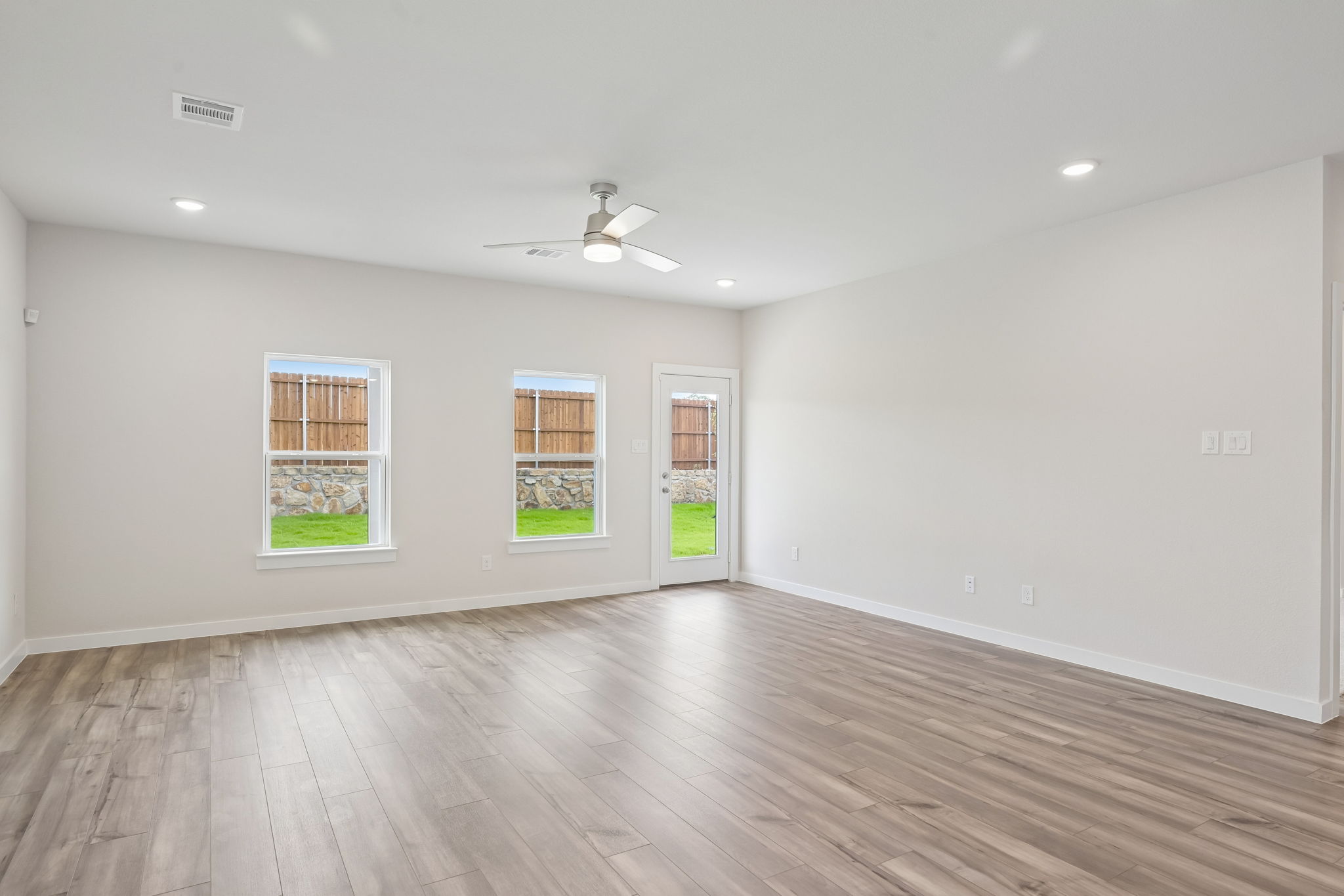 A room with a wood floor and a wood floor with a ceiling fan.