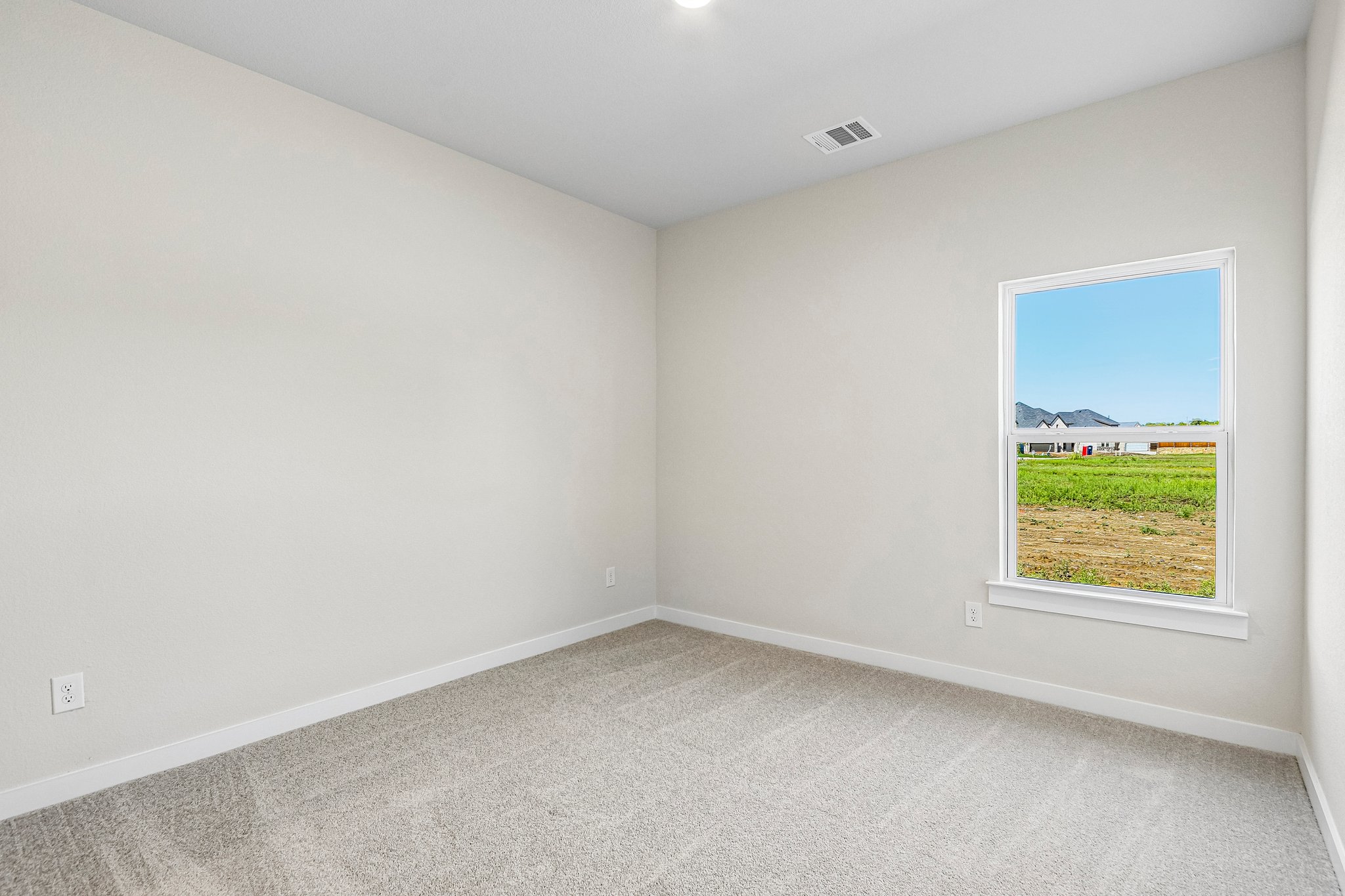 A room with a window and a view of a field.