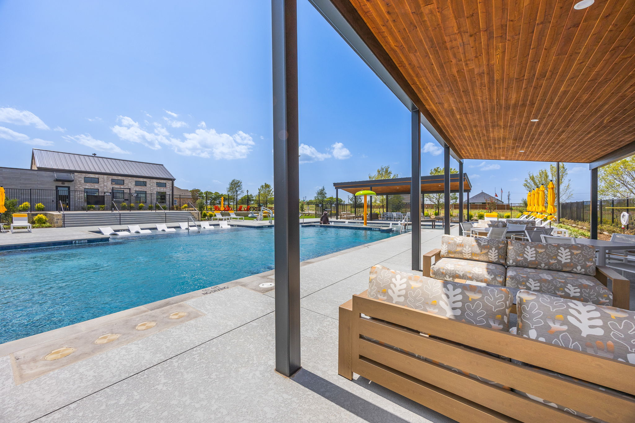 A pool with a lounge chair and umbrella by it.