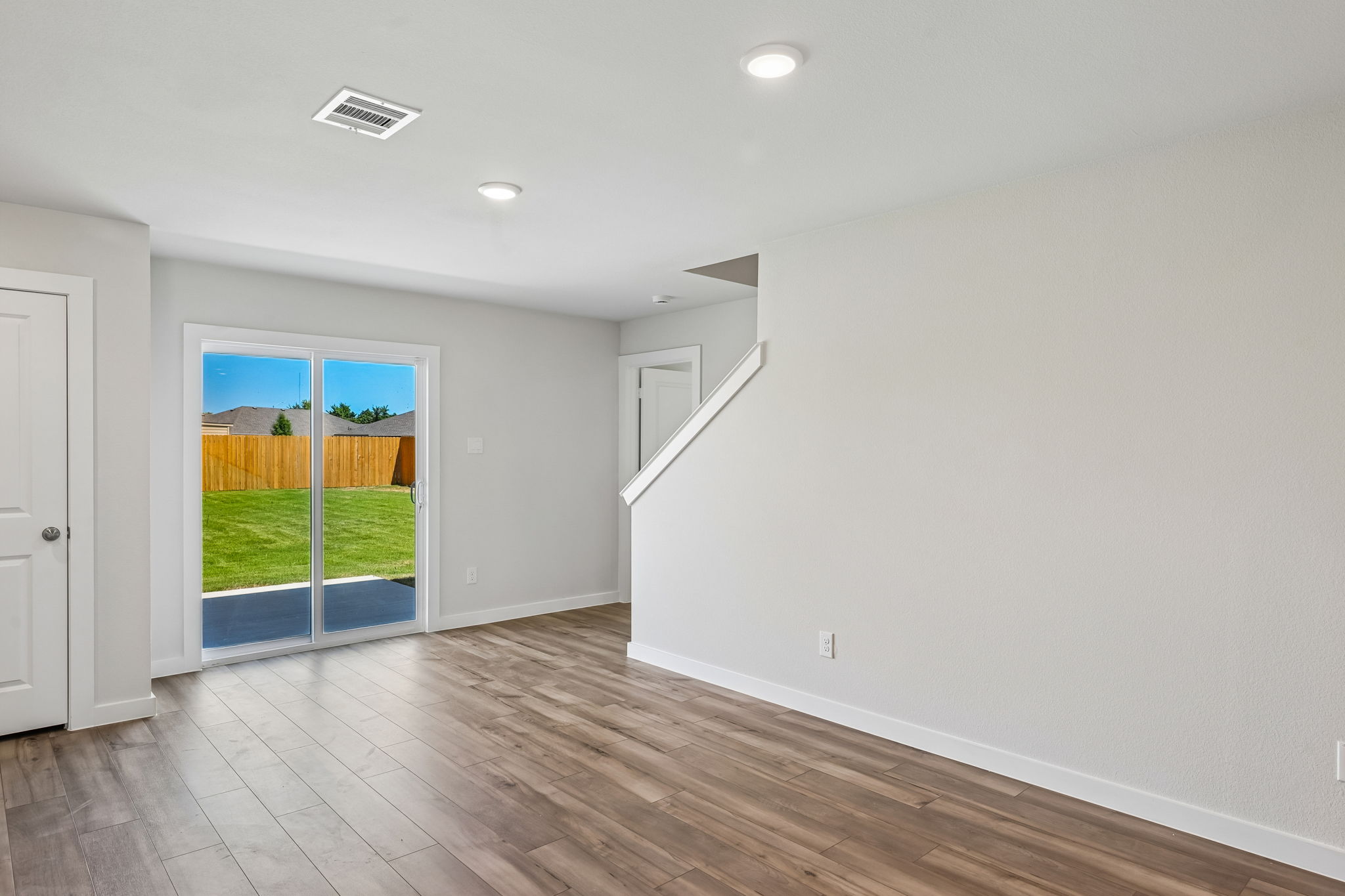 A room with a wood floor and a wood floor with a door and a window with a view.