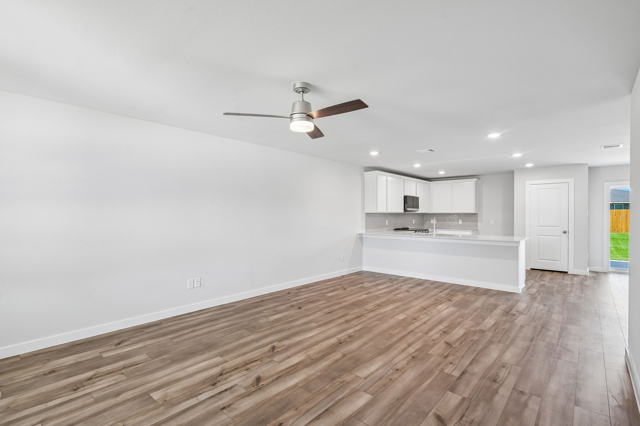 A room with a wood floor and a ceiling fan.