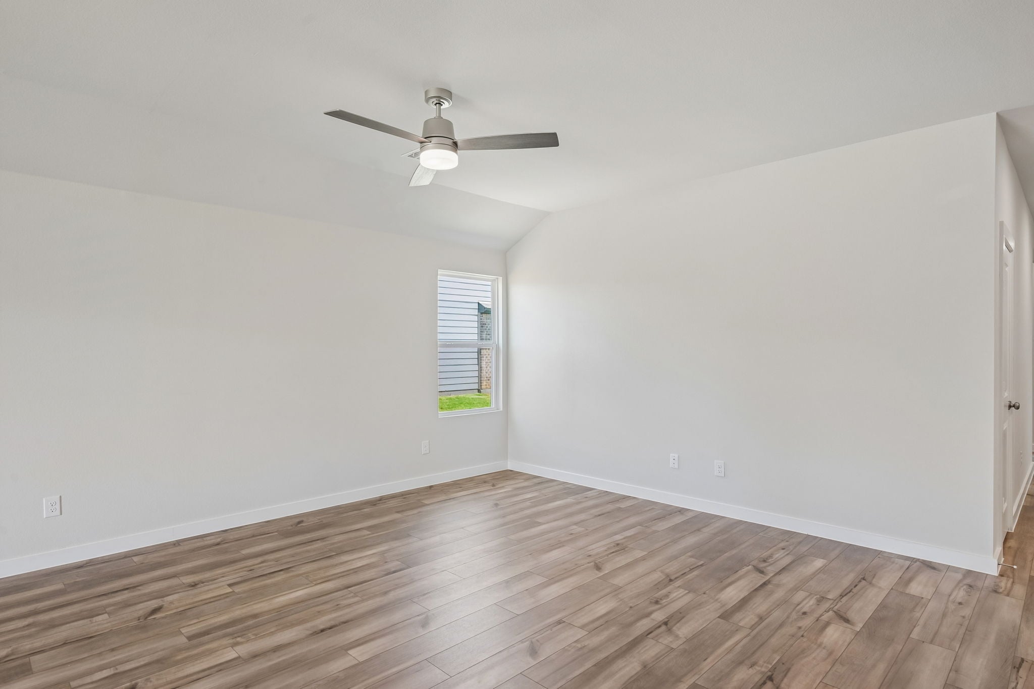 A room with a ceiling fan and wood floor.