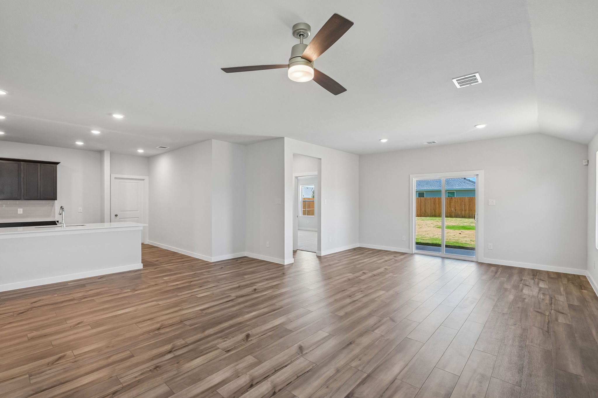 A large empty room with a wood floor and a ceiling fan.
