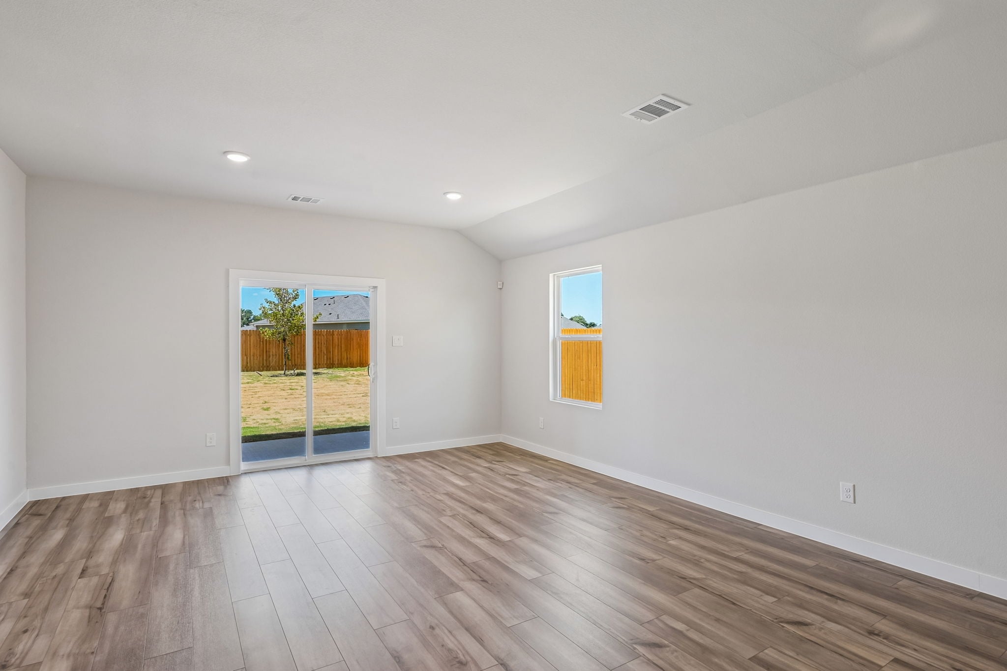 A room with a wood floor and a wood floor with a window.