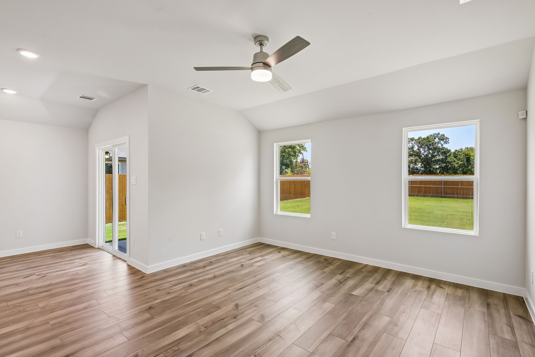 A room with a wood floor and a wood floor with a ceiling fan and a wood floor with.