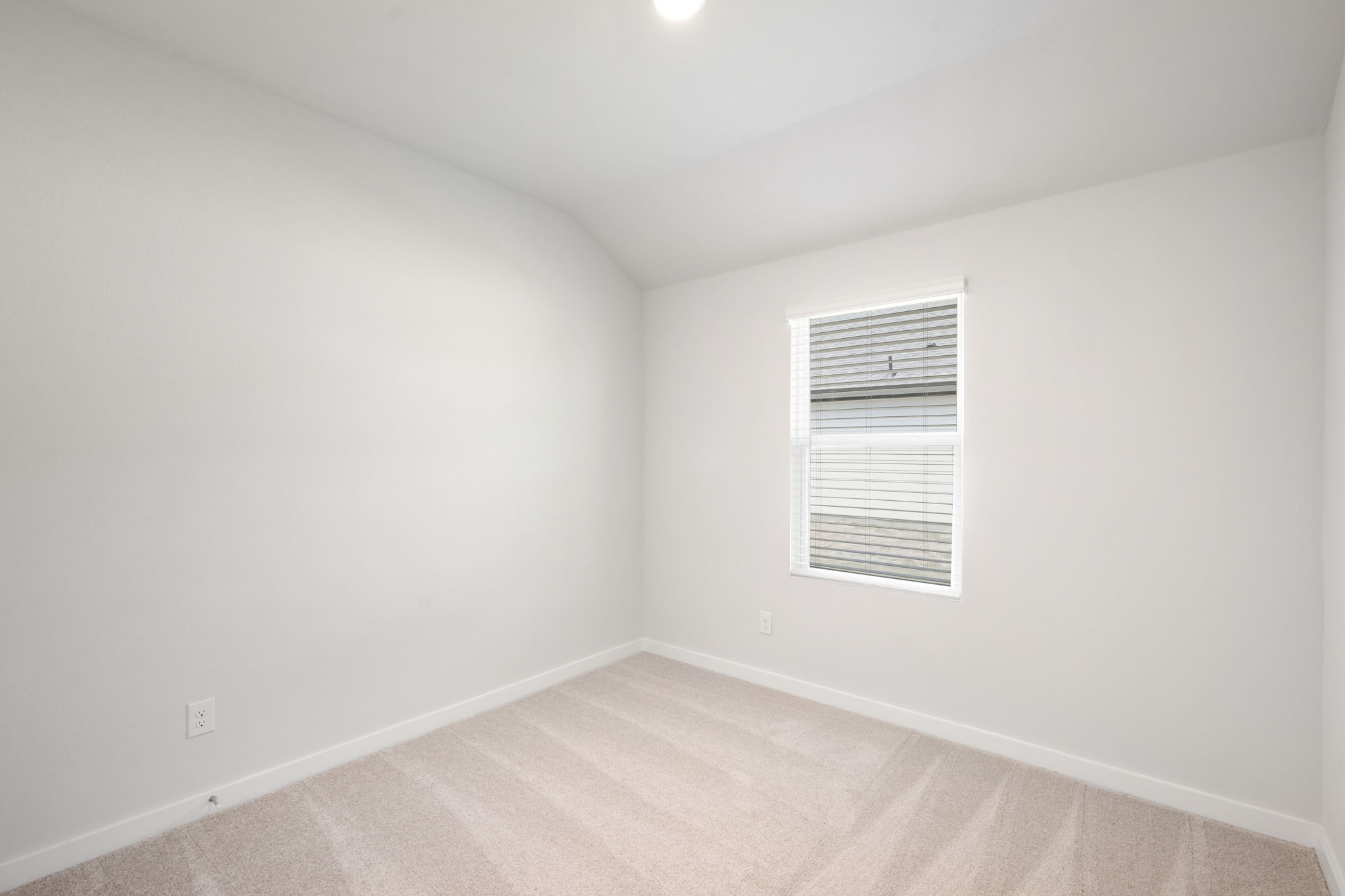 A room with a white wall and a window.