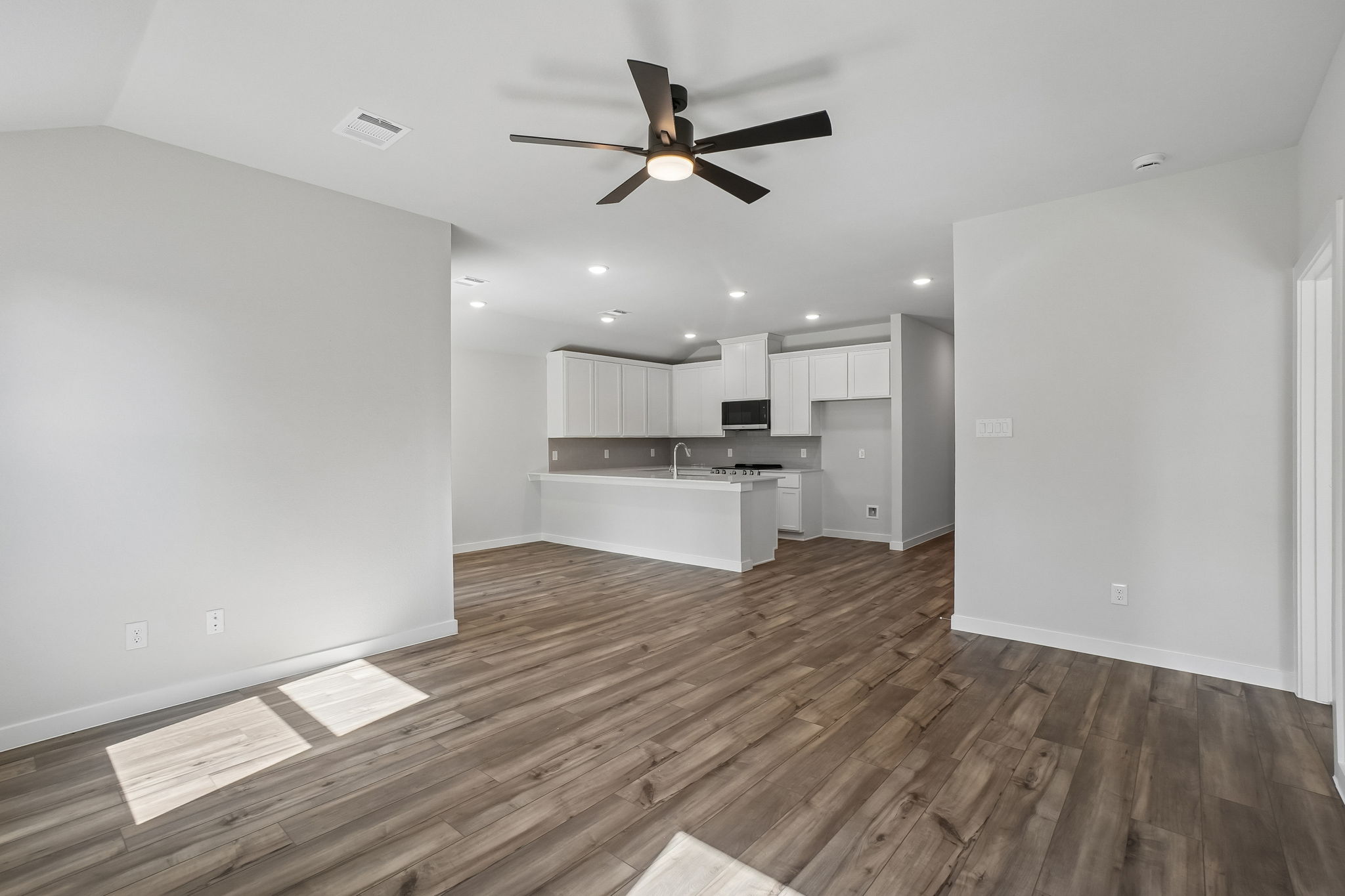 A room with a wood floor and a ceiling fan.
